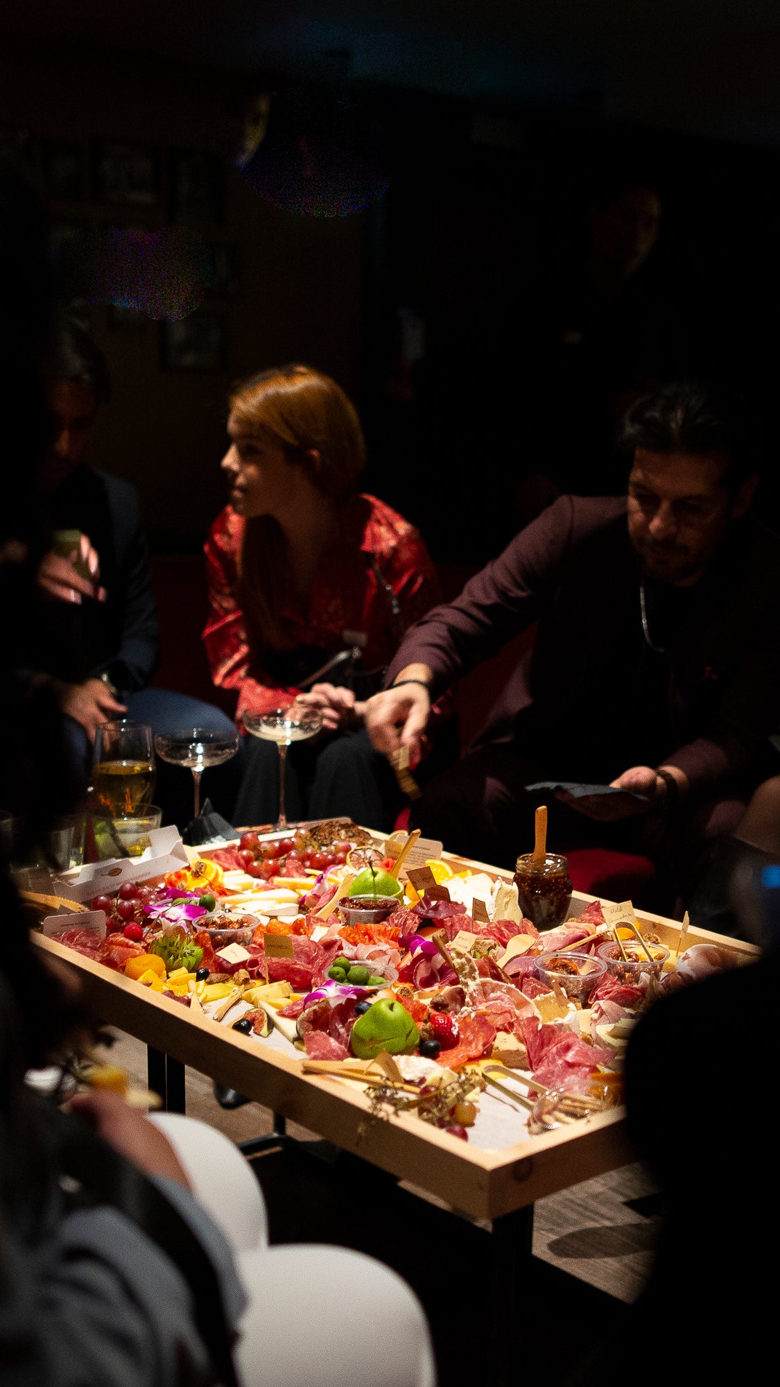 People sitting around a large cheese and charcuterie board in Toronto by The Graze Anatomy